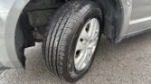 Close-up of a car tire and wheel inside the wheel well, showing tread and a bit of mud on the fender.] ,