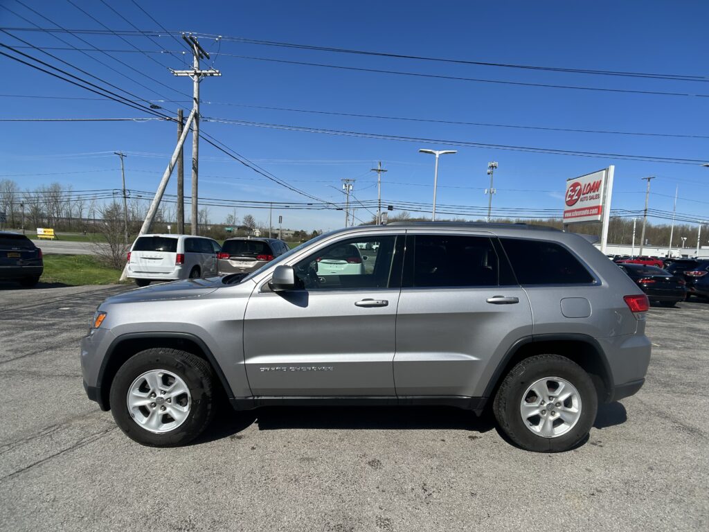 Gray SUV in a parking lot with a tall utility pole and numerous power lines overhead; EZ Loan Auto Sales sign in the background.