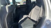 Back seat of a black fabric SUV with three passenger seats and visible seat belts, seen through the car windows at a parking lot outside.