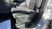 Front passenger seat in a dark car interior with center console and door panel visible, plus a warning label on the door frame edge.
