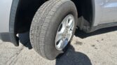 Close-up of a silver SUV wheel with an all-season tire; wheel well and fender visible.