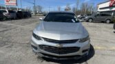 Silver Chevrolet car in a dealership lot with E-Z LOAN Auto Sales signs visible in the background, blue sky overhead.