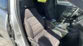 Front passenger and driver seats inside a dark car with the door open, showing the center console and steering wheel.
