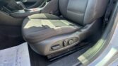 Close-up of a car's front interior showing the driver seat with side adjustment controls, center console, and gear shifter, with a paperDocument on the floor mat nearby.