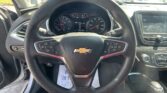 Driver's view of a Chevy steering wheel, instrument cluster, and touchscreen infotainment in a parked SUV.