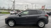 Gray SUV in the foreground of a wet parking lot with other cars and an EZ Loan Auto Sales sign in the distance under a cloudy sky.