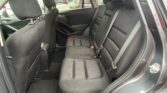 Rear passenger seating in a dark fabric car interior with three seats and visible seat belts.