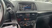 View of a car's center console and infotainment screen with climate knobs; a paper on the floor reads, 'We Take Pride In Your Vehicle'.