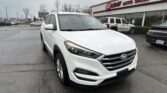 White Hyundai SUV in a parking lot with EZ Loan Auto Sales storefront in the background.