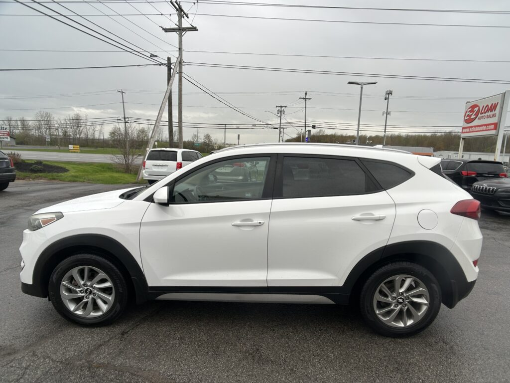 White SUV parked in a dealership lot with power lines overhead and an EZ LOAN Auto Sales sign in the background