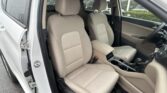 Interior of a beige-cloth SUV with front seats, center console, and steering wheel on the right; rain on the windows.