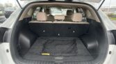 Open SUV trunk with folded third-row seats and beige interior; a black mesh cargo net lies on the floor in back.