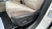Beige car interior with front seat and center console; visible seat adjustment controls and red seatbelt buckle by the seat edge.