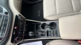 Interior of a car's front cabin: beige seats, center console, gear lever, cupholders, and a Tucson floor mat visible.