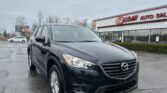 Black Mazda SUV in the dealership lot, with EZ Loan Auto Sales storefront and cloudy sky in the background, parked at an angle in the foreground.