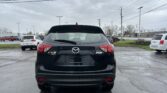 Rear view of a black Mazda CX-5 AWD SUV parked in a parking lot on a cloudy day, with power lines overhead