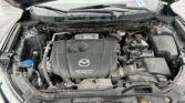 Car engine bay with hood open, showing SkyActiv Technology engine cover and surrounding components.