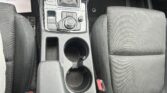 Center console of a car showing an automatic gear shift, control knob, and two cup holders between the front seats.