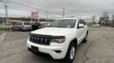 White SUV in a dealership lot on a cloudy day, with other cars and dealership signs in the background (E-Z Loan Auto Sales).