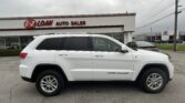 White SUV (Grand Cherokee) in front of E-Z LOAN AUTO SALES storefront; cloudy sky above, dealership sign visible.