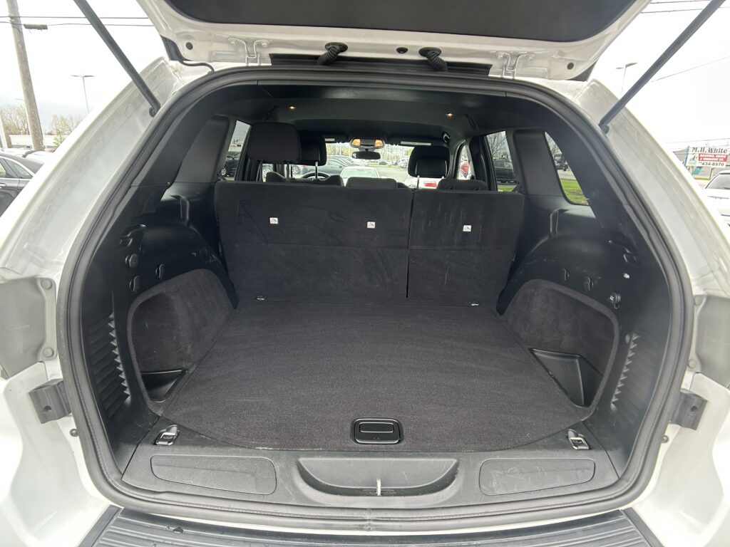 Open SUV trunk with rear seats up, showing large empty cargo area and third-row headrests visible.