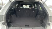 Open SUV trunk with rear seats up, showing large empty cargo area and third-row headrests visible.