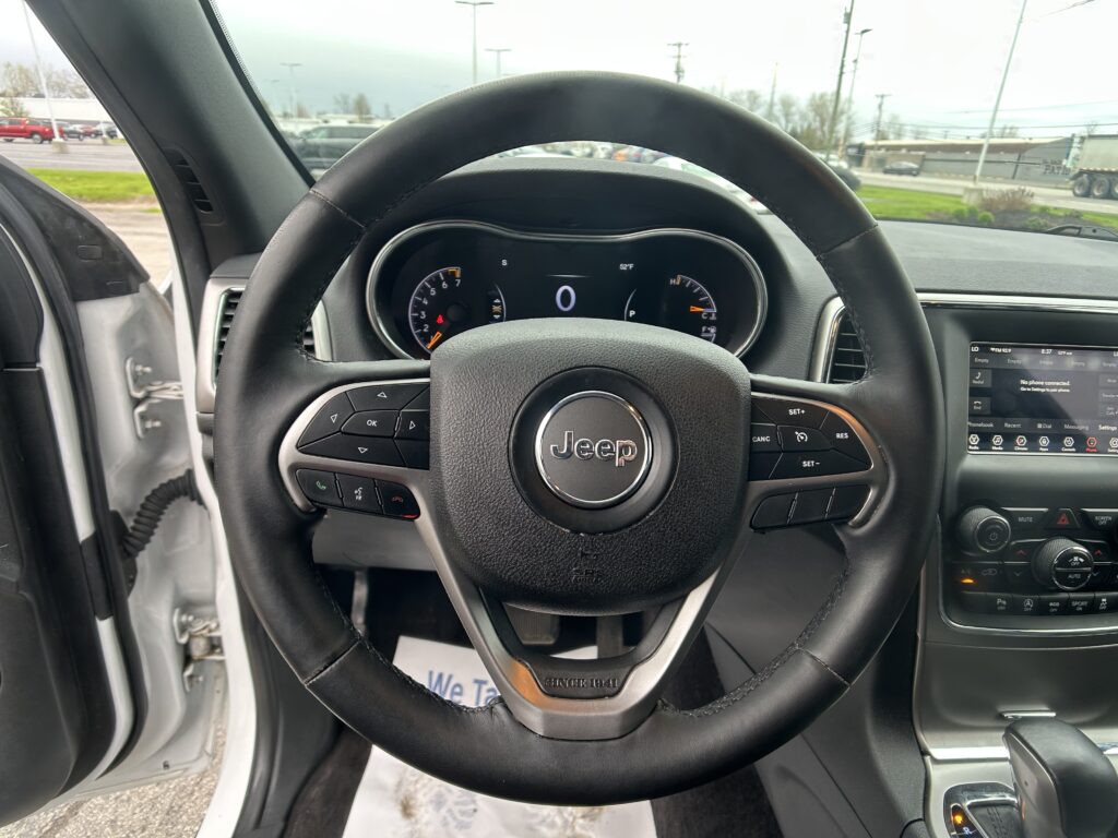 Steering wheel of a Jeep with a digital dashboard and center console in view from the driver’s seat position