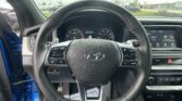 View from the driver’s seat of a car interior showing the steering wheel, instrument cluster, and the right-side touchscreen display.