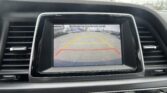 Infotainment screen showing rear parking camera with yellow guide lines and a safety message, inside a car cockpit.