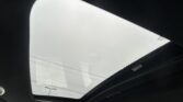 Interior view of a car with the sunroof open, revealing a pale sky beyond the glass