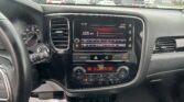 Dashboard interior showing a touchscreen radio display tuned to 1270 kHz with climate controls below in a rain-soaked car interior.