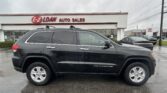 Black SUV (Grand Cherokee) parked in front of a white auto dealership with an 'E-Z LOAN AUTO SALES' sign on the building.