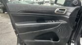 Car door interior panel with window controls; rainy parking lot visible through the window.