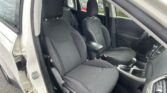 Open car door revealing the front seats and center console of a white SUV, with black fabric upholstery and honeycomb pattern.
