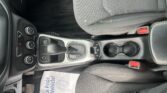 Interior of a car showing the driver-side center console, gear shifter, cup holders, and a cloth seat with wear and stains.