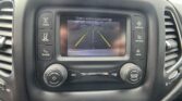 In-dash display showing a rear‑view camera feed with parking guide lines (green, yellow, red) and the message 'Check entire surroundings'.