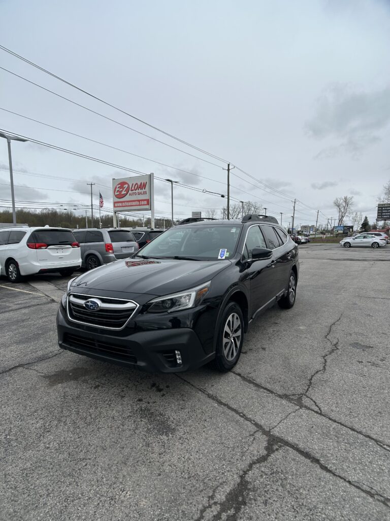 Dark SUV in a car dealership lot with an EZ LOAN AUTO SALES sign in the background on a cloudy day