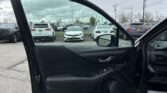 Open car door from inside a vehicle, showing a view of a parking lot with white SUVs lined up and other cars in the background.