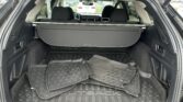 Open SUV trunk with multiple rubber cargo mats piled on the floor and a retractable cargo cover; rear seats are visible in the background.