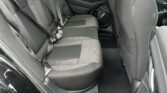 Interior of a black SUV rear cabin with gray fabric seats and three-point seat belts visible in the back row.