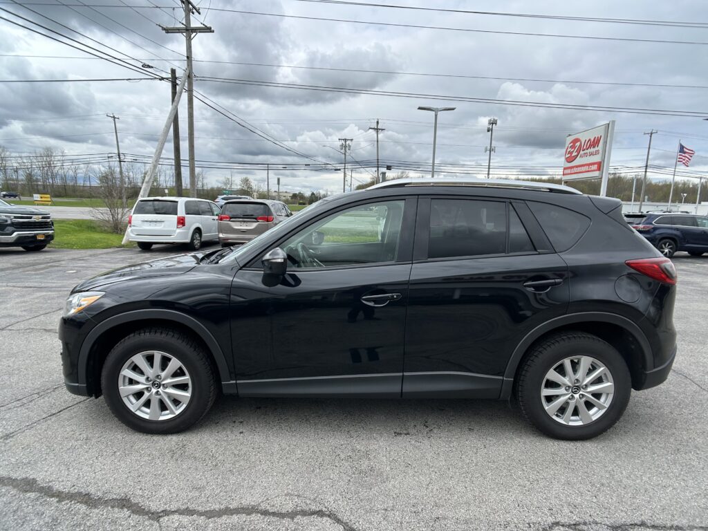 Black SUV parked in a lot with a cloudy sky and an EZ Loan Auto Sales sign in the background.