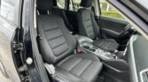 Front seats and center console of a black car with the driver’s door open, showing headrests and cupholders in the foreground.
