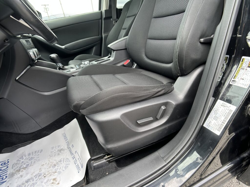 Front passenger area of a car interior showing black fabric seats, center console with gear shifter, and door panel with seat belt may be visible.