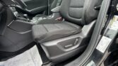 Front passenger area of a car interior showing black fabric seats, center console with gear shifter, and door panel with seat belt may be visible.