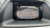 Rear-view camera display in a car showing yellow parking guide lines and the safety message 'Please Check Surroundings For Safety' at the bottom.