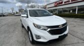 White Chevrolet SUV parked in a dealership lot in front of an E-Z Loan Auto Sales storefront.