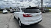 White Chevrolet SUV parked in a car lot with other vehicles and cloudy sky above.