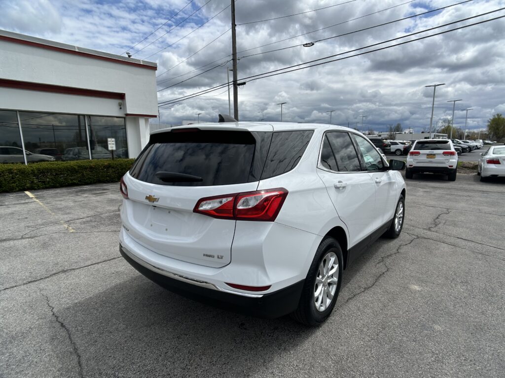White Chevrolet SUV in a parking lot near a storefront with cloudy skies above and power lines overhead