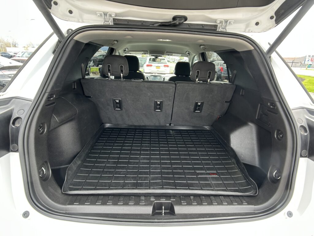 Open SUV trunk with three-row seating upright and a ribbed black cargo mat visible in the cargo area on the floor.