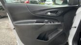 Interior of a white car door panel with the window/lock controls visible, and a parking lot of trucks and SUVs seen through the open window.